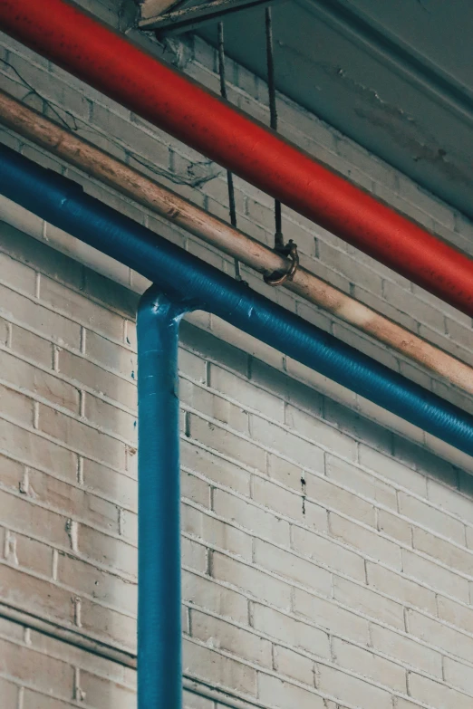 a red and blue pipe connected to brick wall