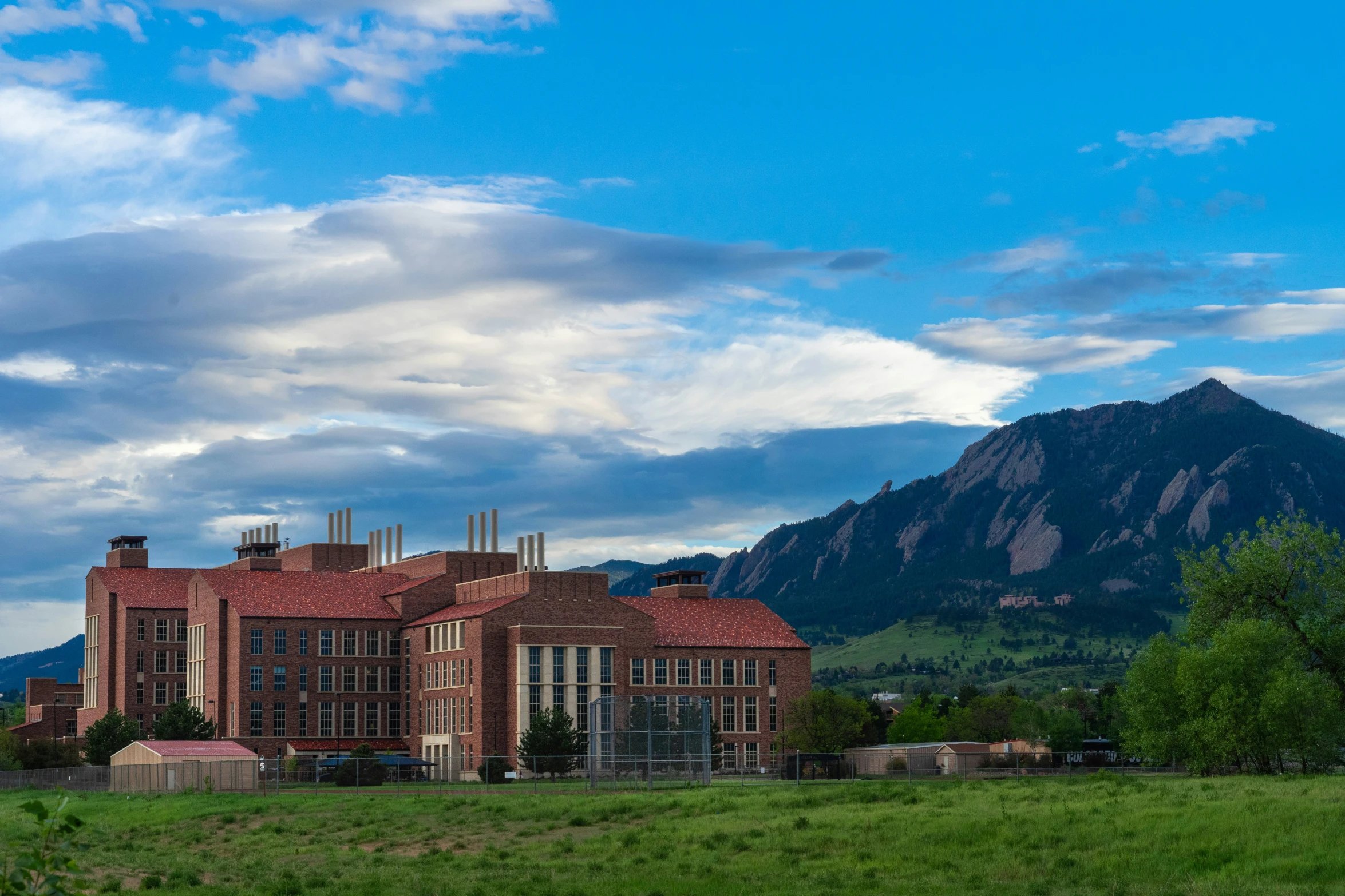 a building with a large tower in the middle of a field with mountains behind it