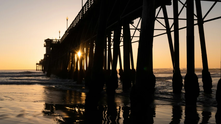 the sun peeks through an old, run down pier