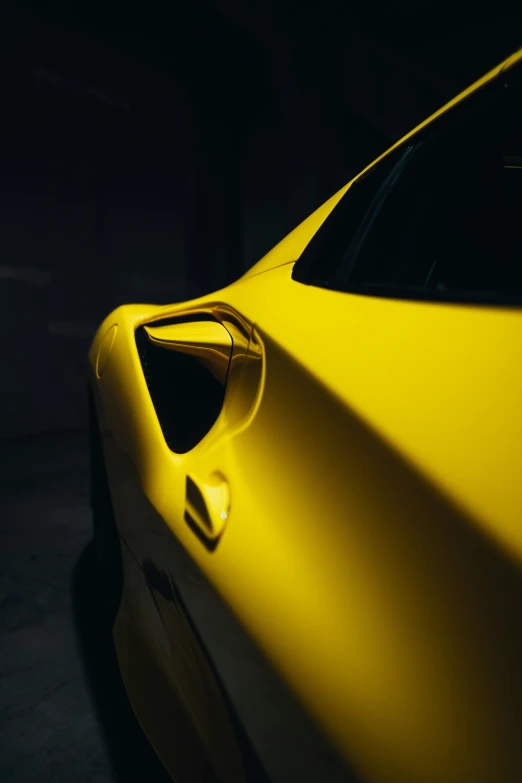 the back side of a yellow sports car in the dark