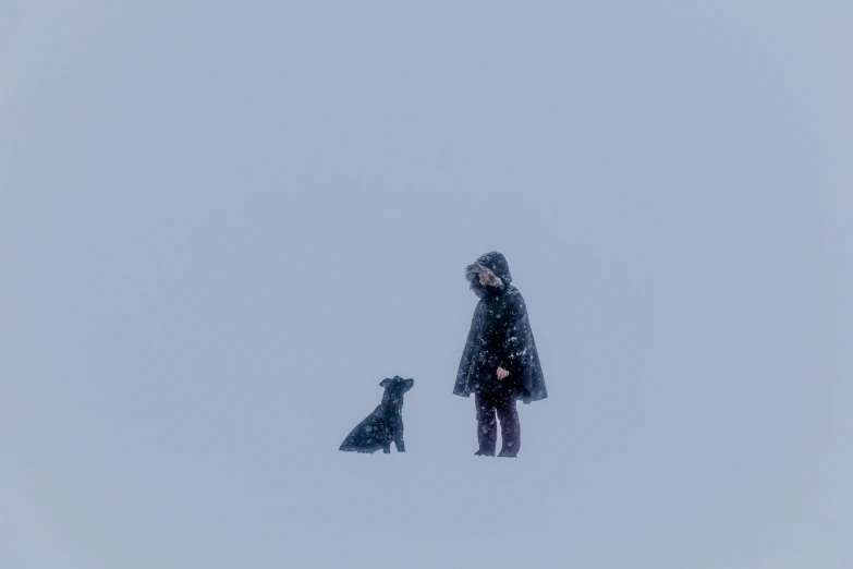 the woman and the dog are standing in the snow