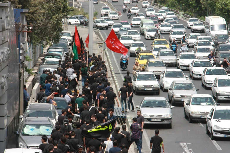 a parade of people marching and holding flags in traffic