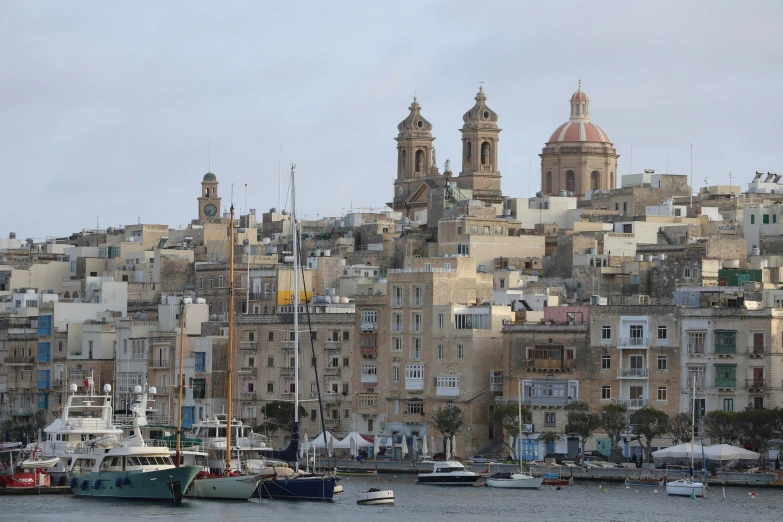 some very pretty buildings on a hillside with some boats in the water