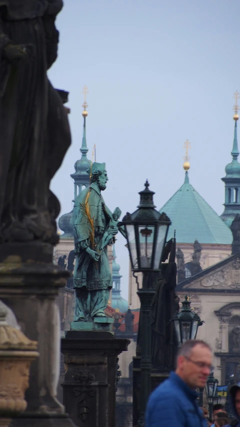 a man standing next to a statue near some lamps