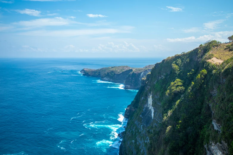 a view from atop of a cliff with blue water