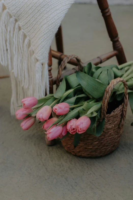 a basket filled with lots of pink flowers next to some green leaves