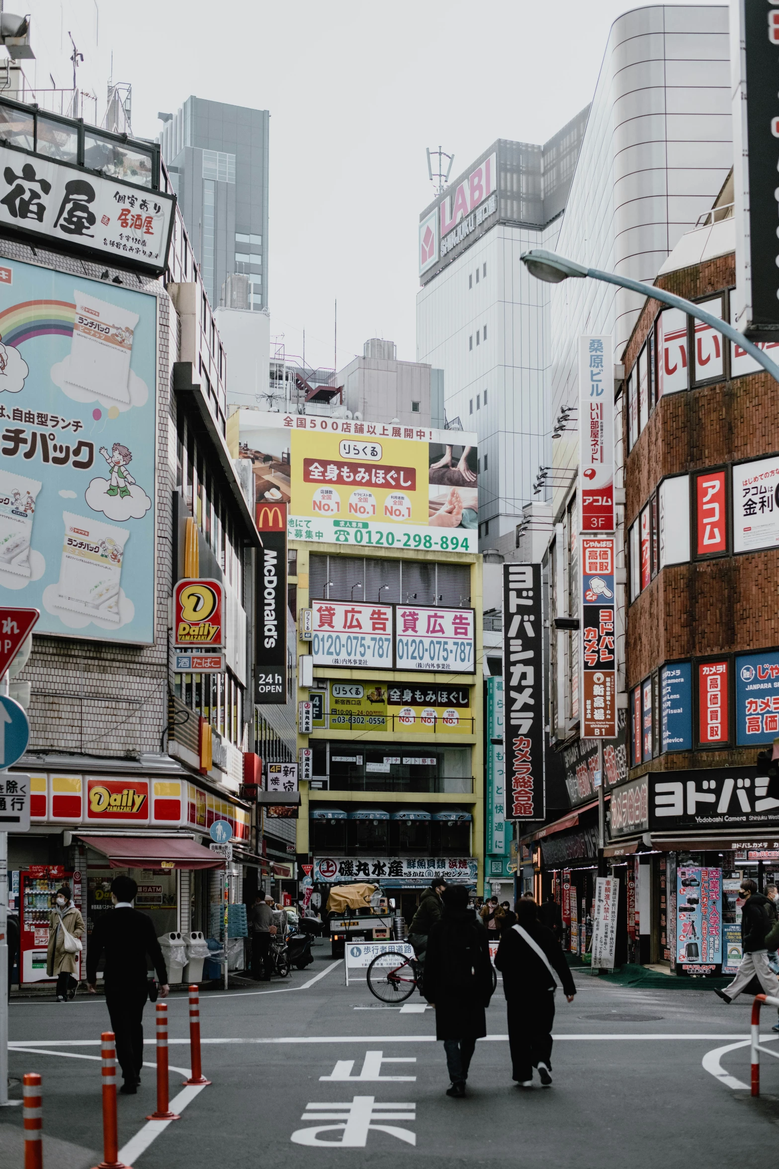 several people walking in a city with buildings and billboards