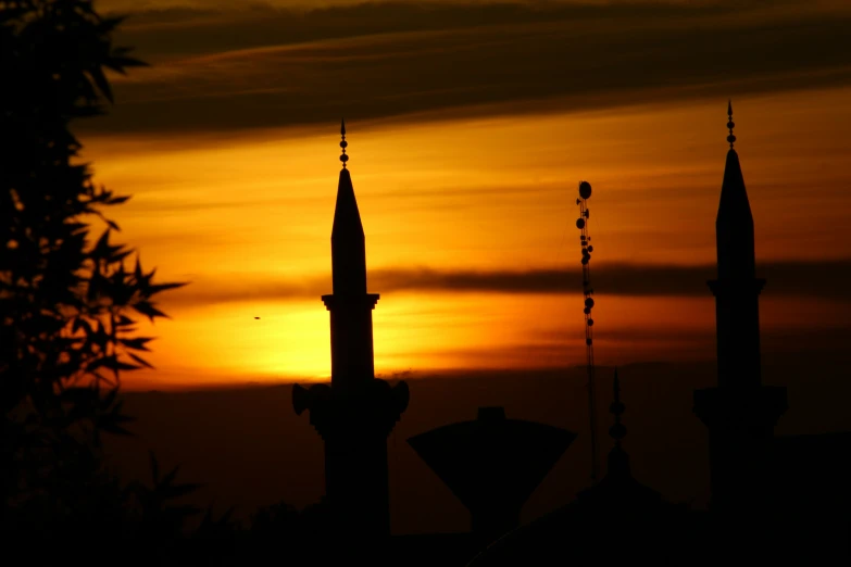 a sunset with some type of building in silhouette