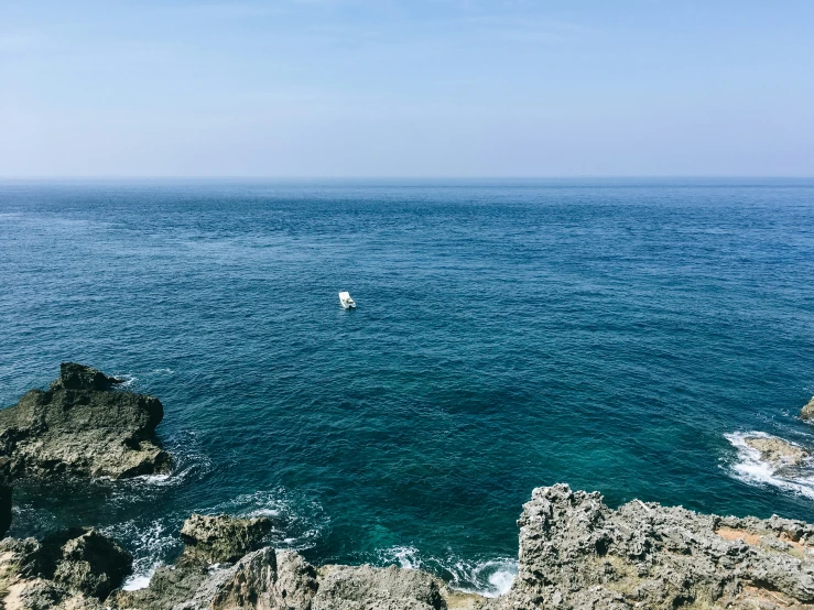 a boat in the middle of the ocean on a clear day