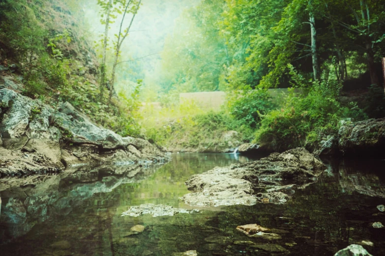 the stream is surrounded by rocky hills and green trees