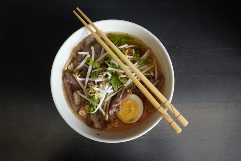 bowl filled with soup, soup, and a pair of chopsticks