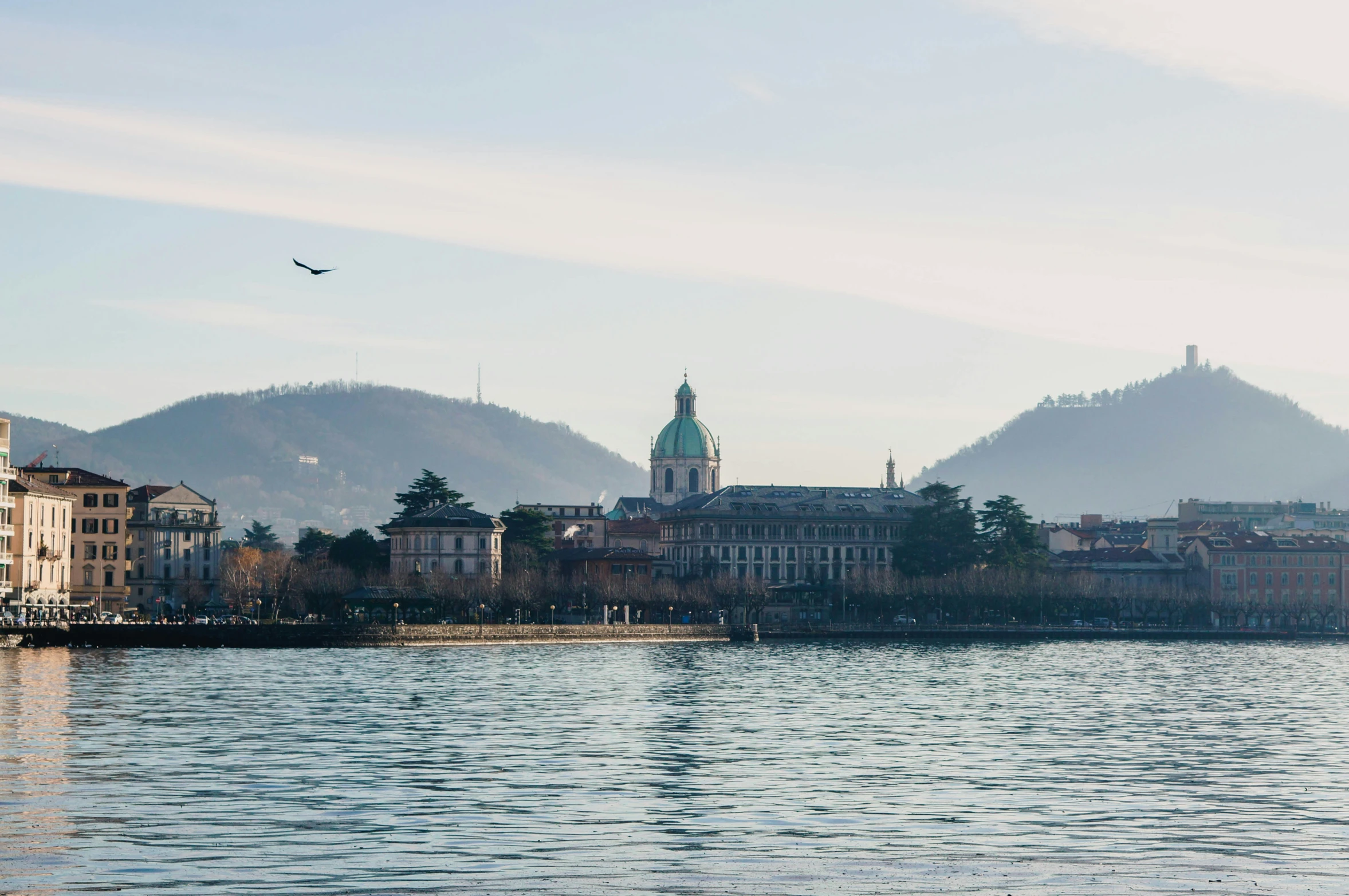 a body of water with buildings and hills in the background