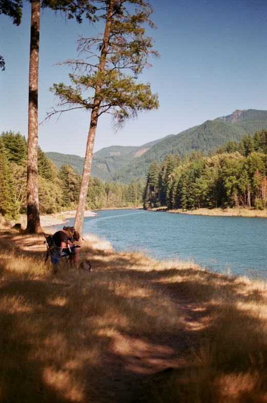 two people on a bench in front of a mountain lake