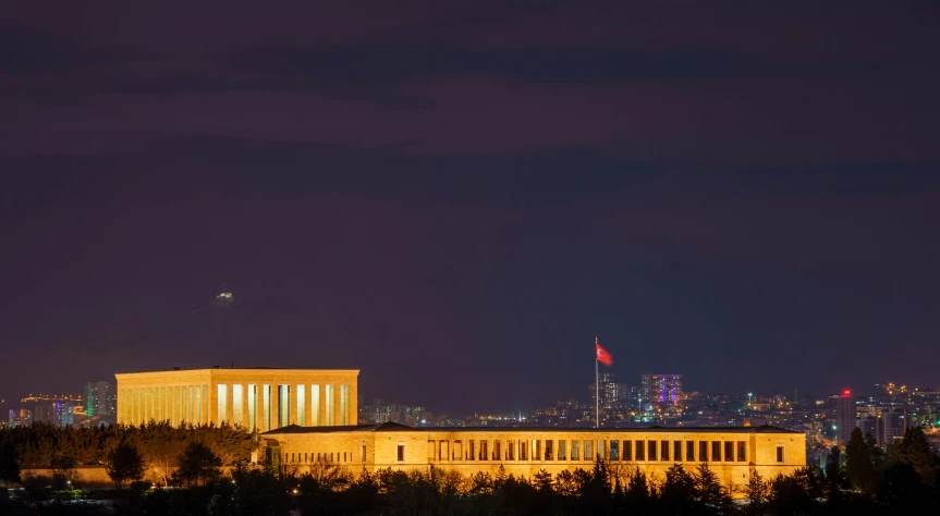 a city skyline at night with an airplane in the distance