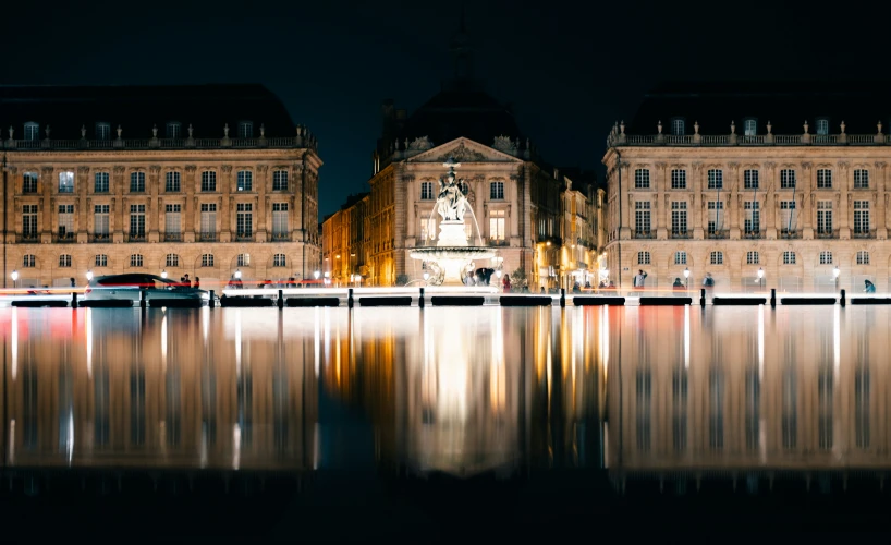 a large building sitting next to the water at night