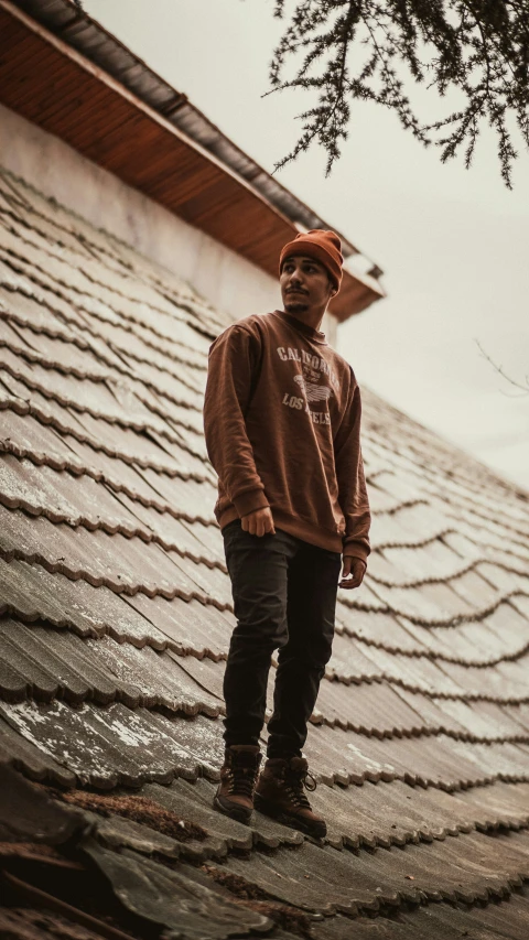 man standing on the edge of a roof wearing a hat
