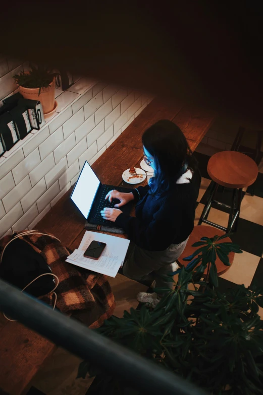 a young woman sitting at a table using a laptop