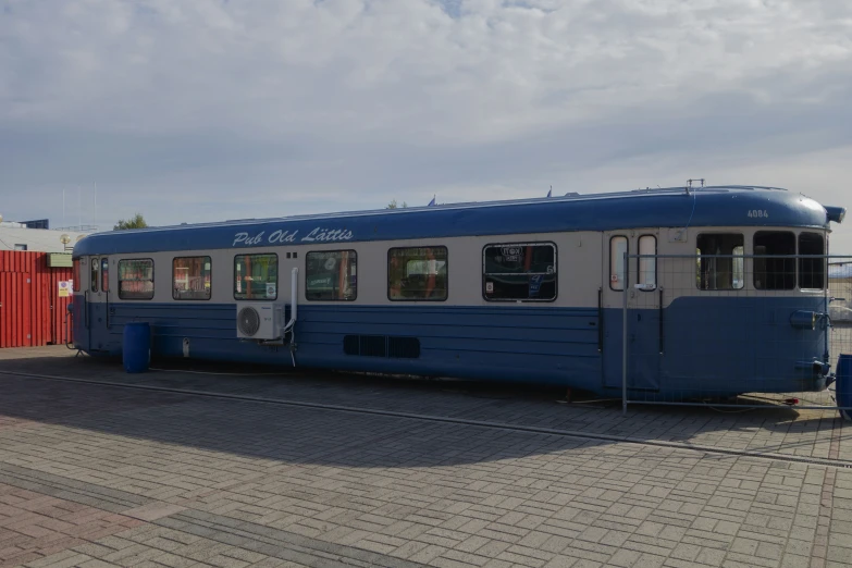 an old blue and white bus on a brick street