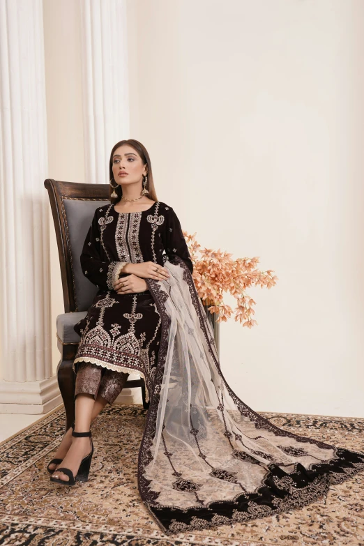 a beautiful young woman sitting on a chair wearing a black dress