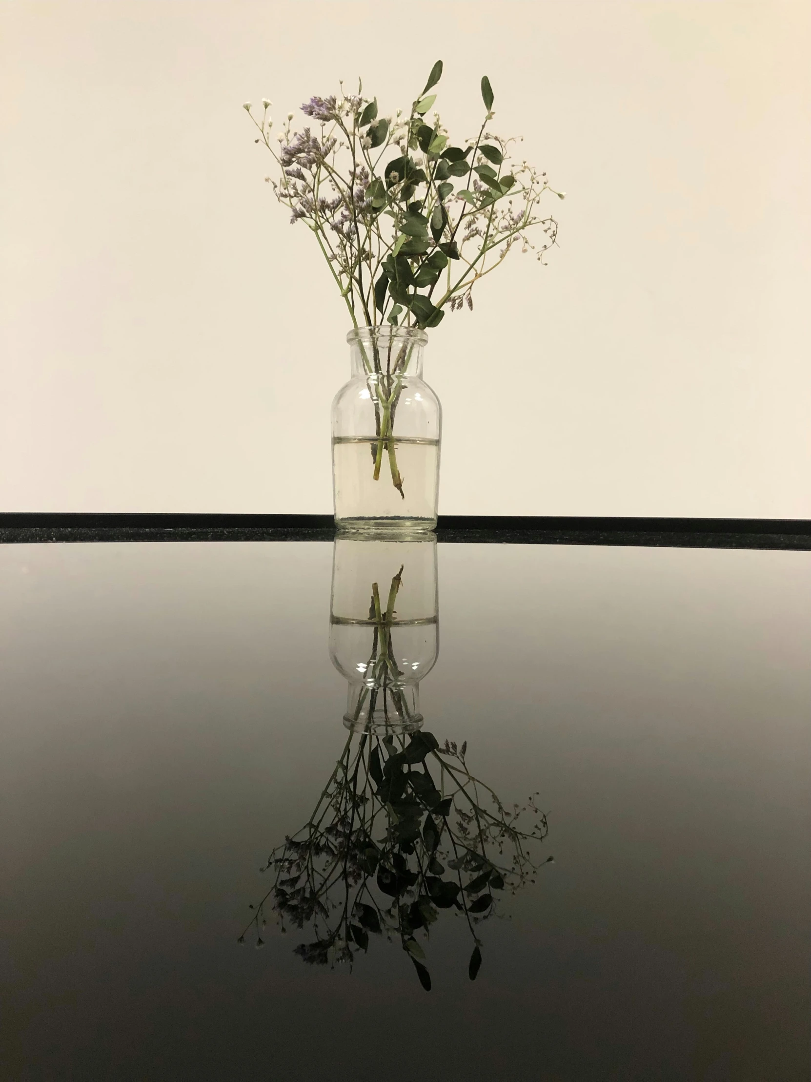 a single bud vase full of flowers sits on a surface