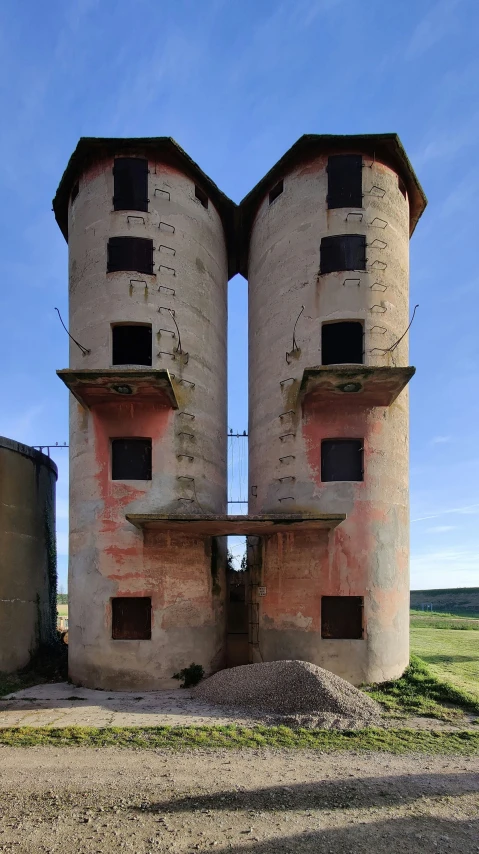 two water storage silos facing each other on a dirt field