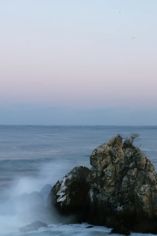 a rock formation in the middle of water with a body of water behind it