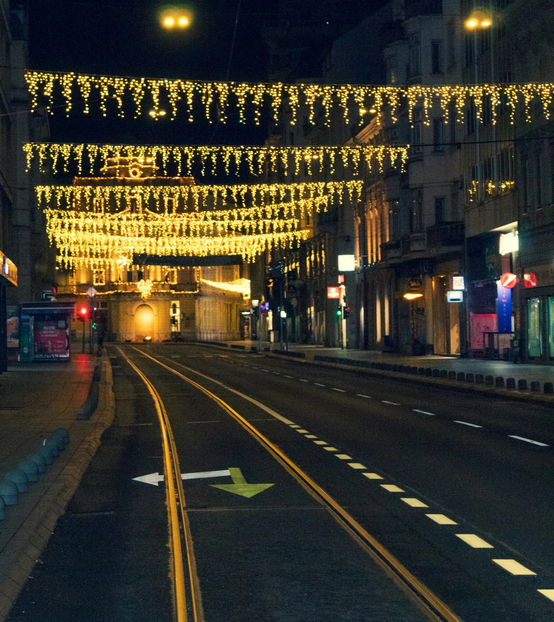 an empty train track during the night, with holiday lights strung on it