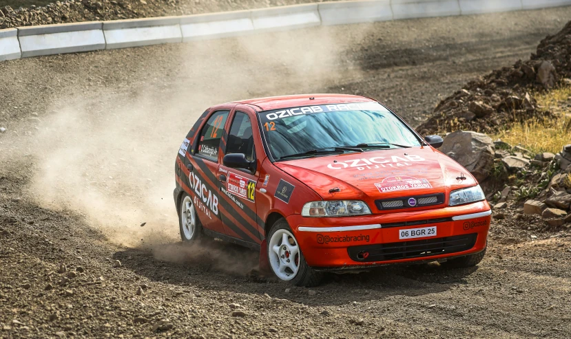 an orange car driving down the road in the dirt