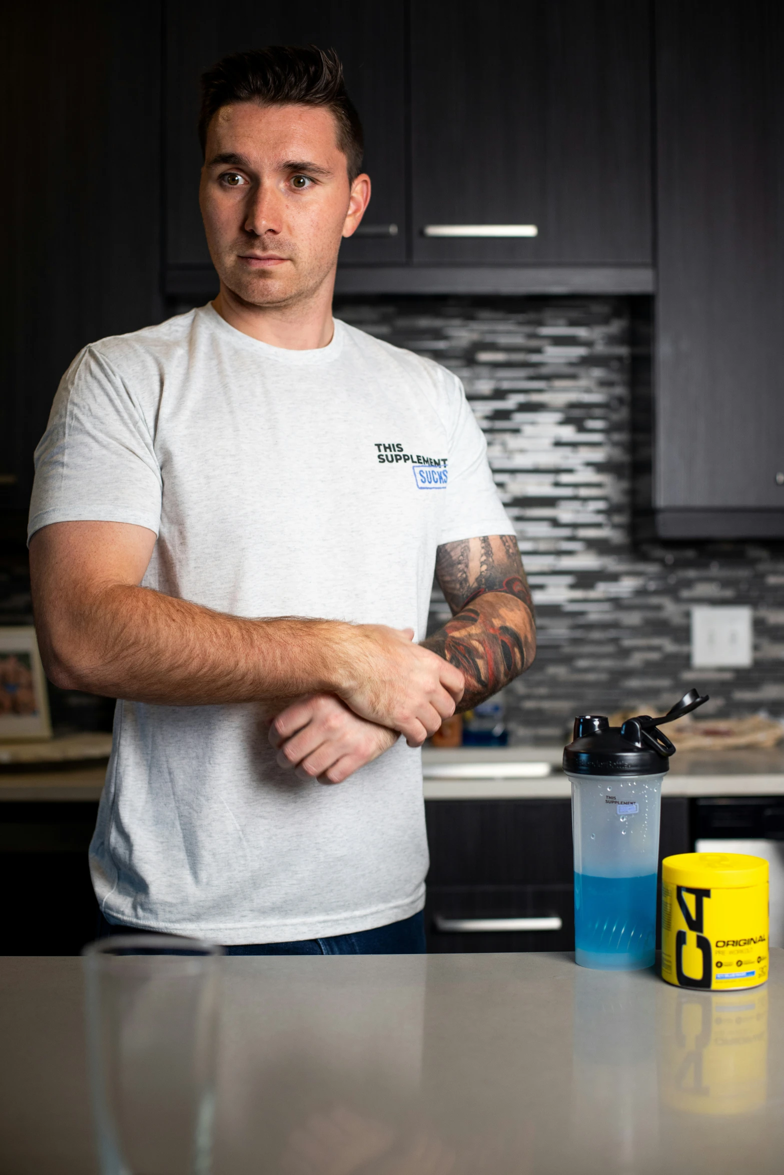 a man with a tattoo standing next to a counter in a kitchen