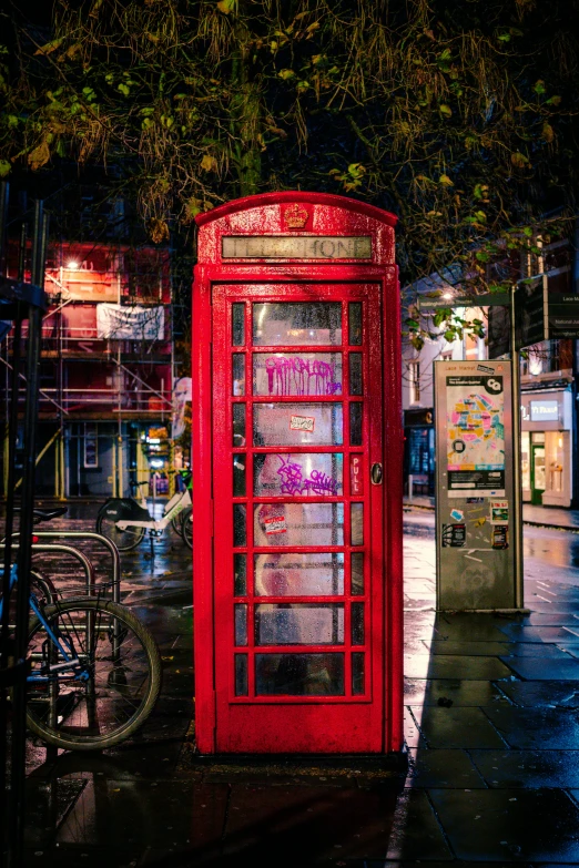 a red phone booth on a wet street