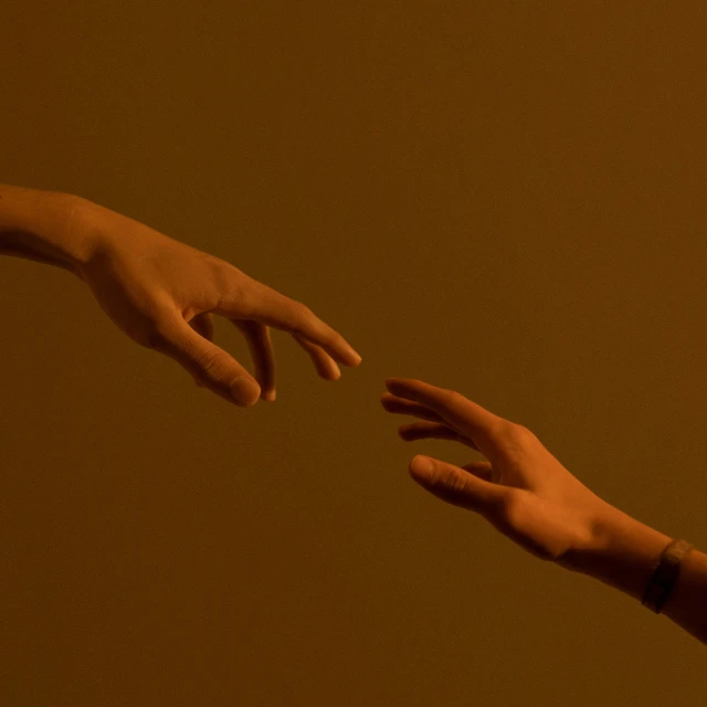 a person reaching out their left hand toward another hand