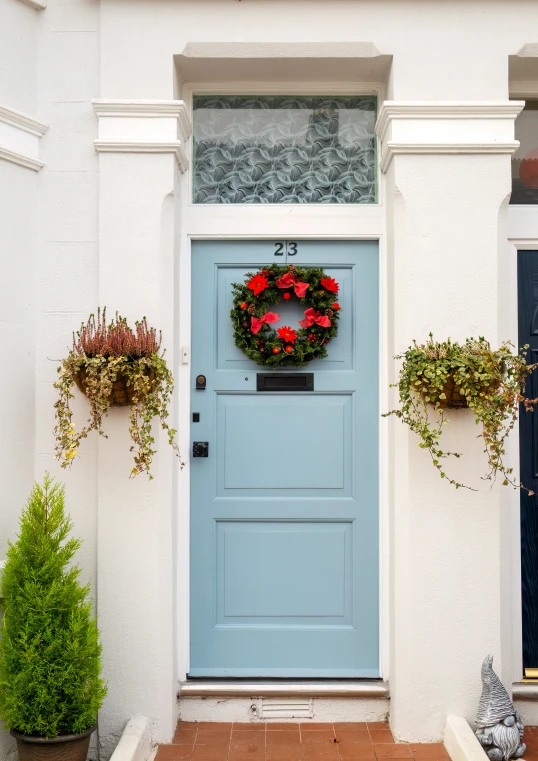 a blue door with white trim has a wreath and potted plants