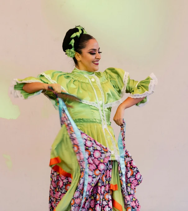 a woman in green dress dancing with her arms spread out