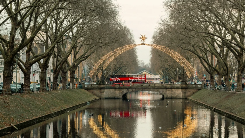 a red bus is riding along on the tracks near a river