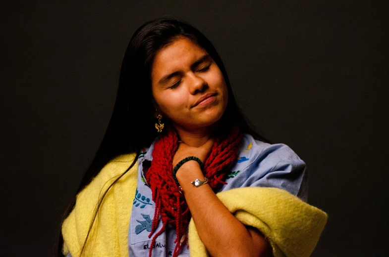 a woman in yellow scarf and scarf around neck with her hand under the collar