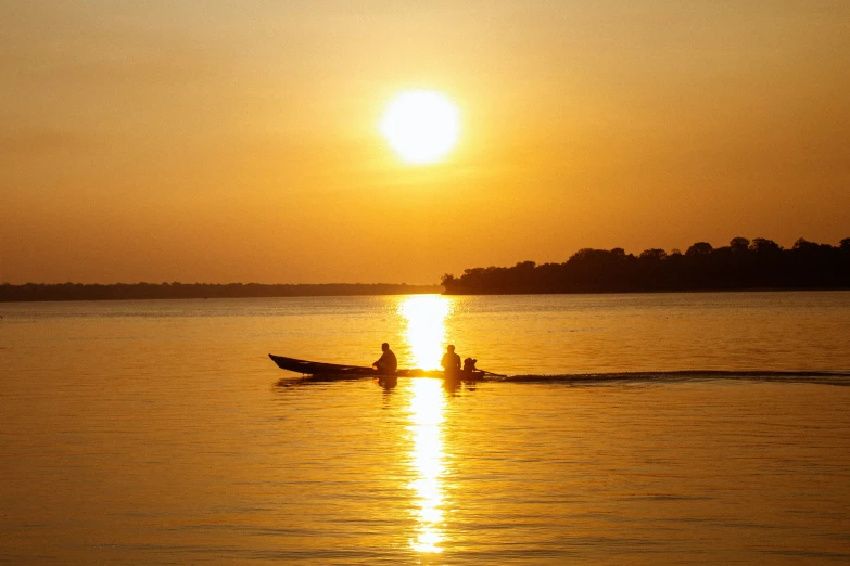 two people riding in a boat on the water at sunset