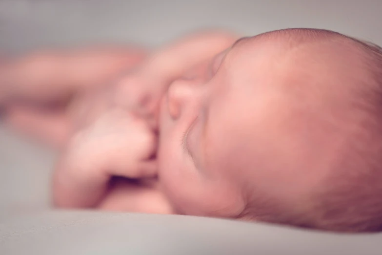 a baby with its face on the side of a bed