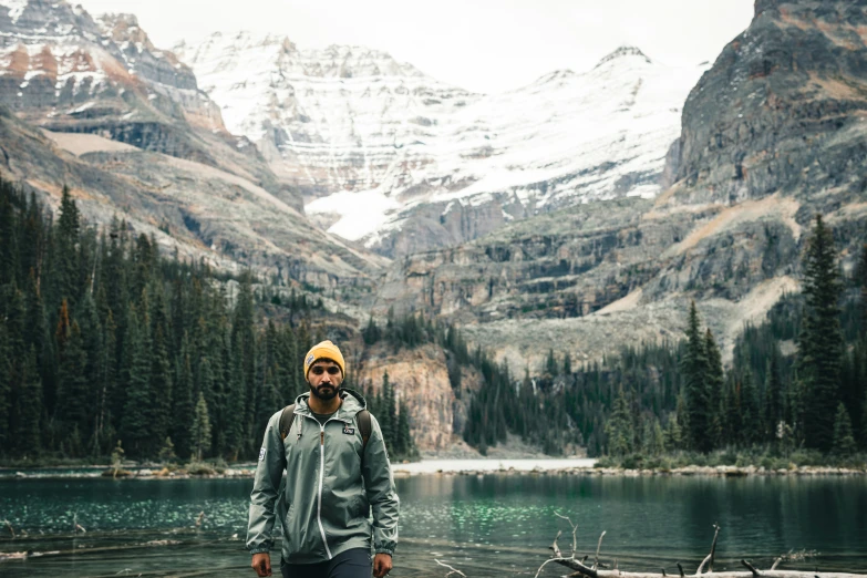 a man standing on top of a mountain next to a lake