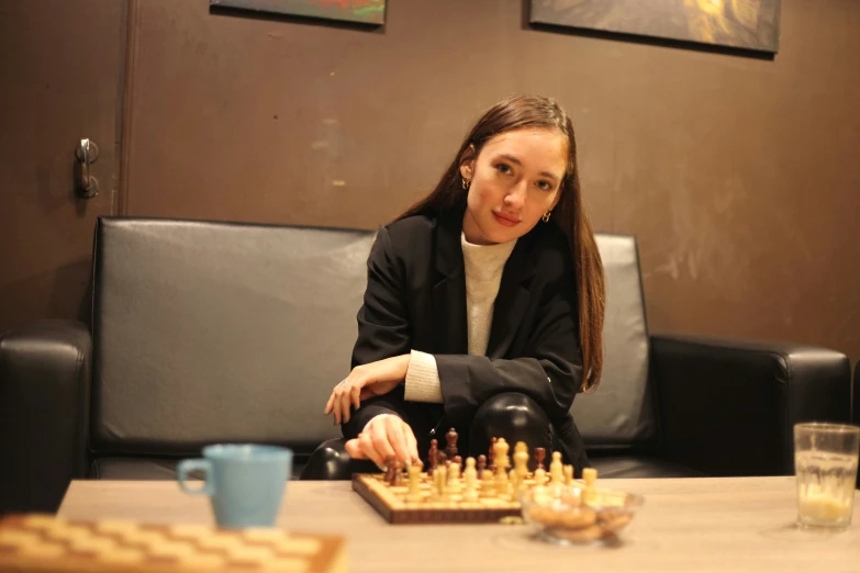 a woman sitting at a table with some chess board and pieces