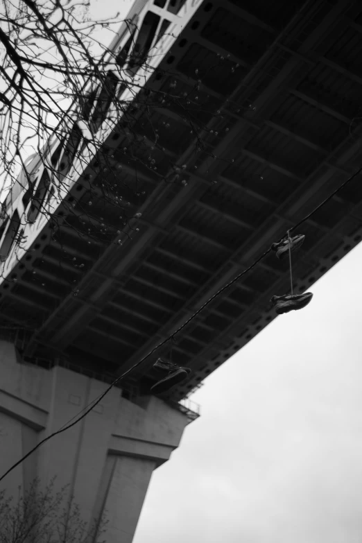 a sneaker hanging on a line in front of a bridge