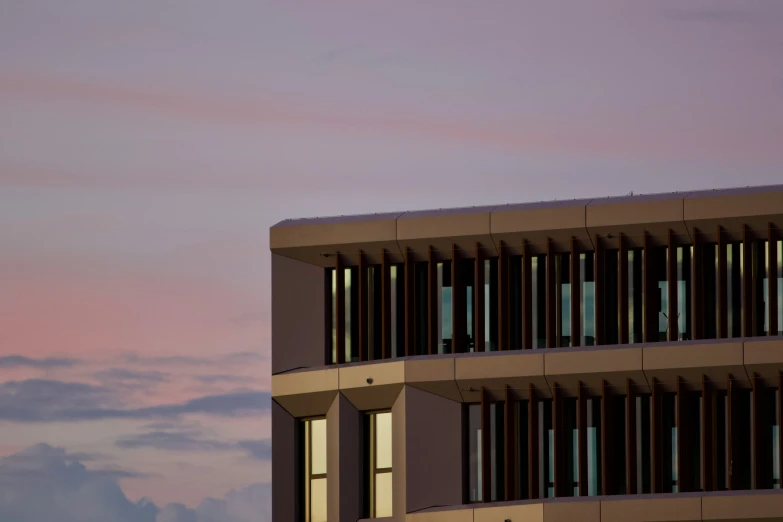 the back side of a building with lots of windows at dusk