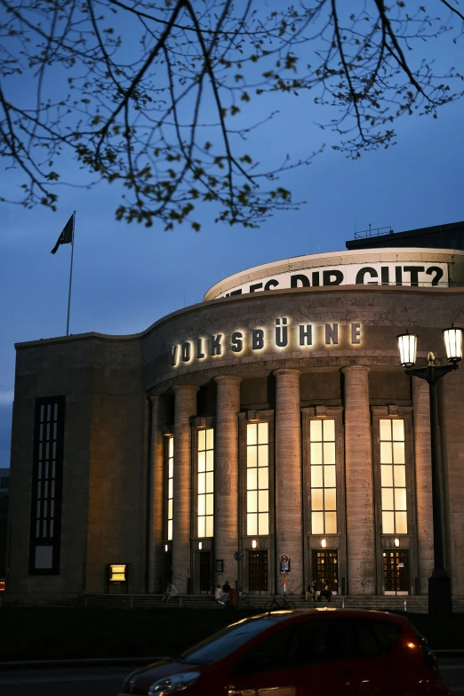 a very tall building with many windows near a red car