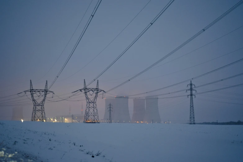 electricity lines overcast on snowy hill with power poles