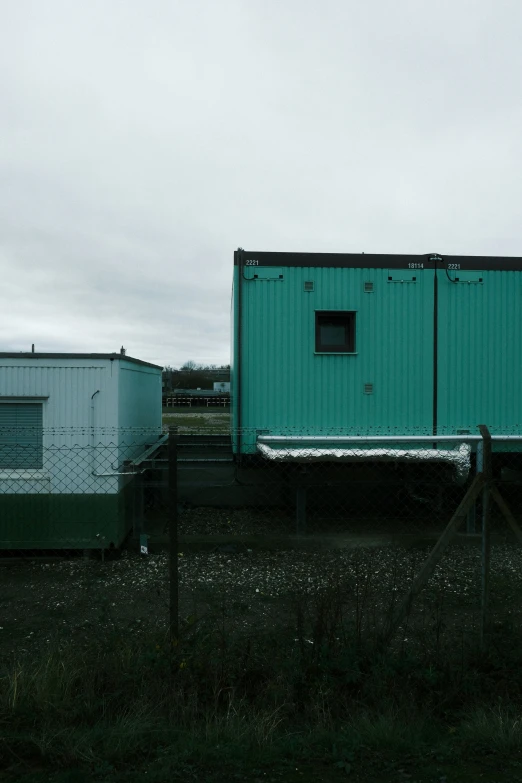 a large green building sitting on top of a dirt field