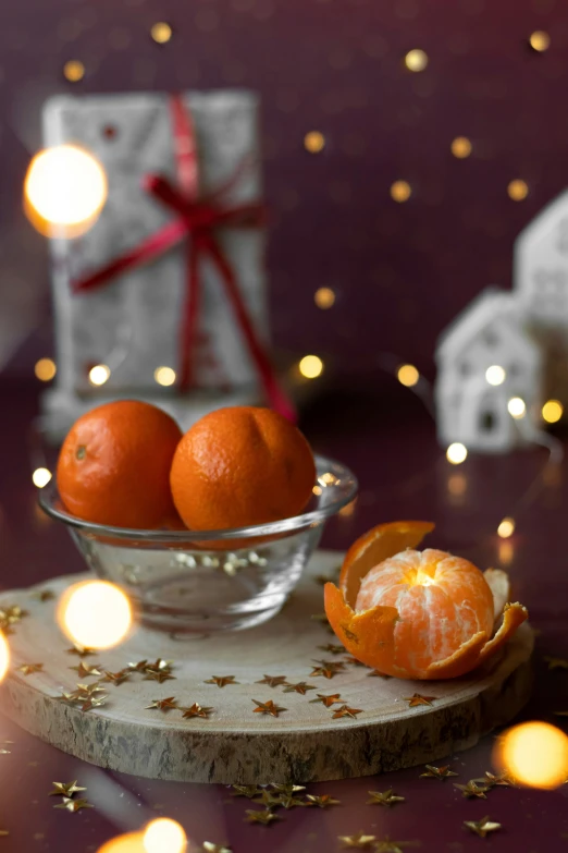 a glass bowl with oranges sits on a table