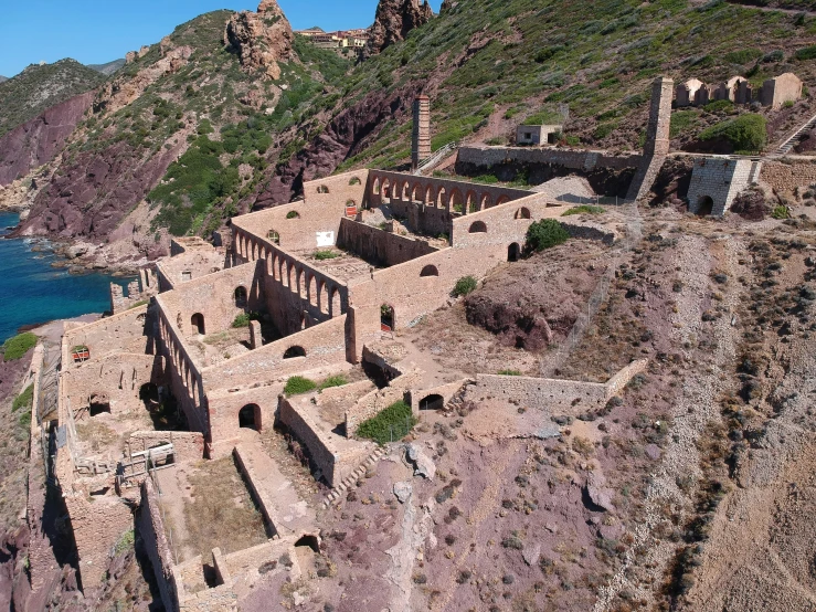 an aerial view of an abandoned building perched on a hillside overlooking water