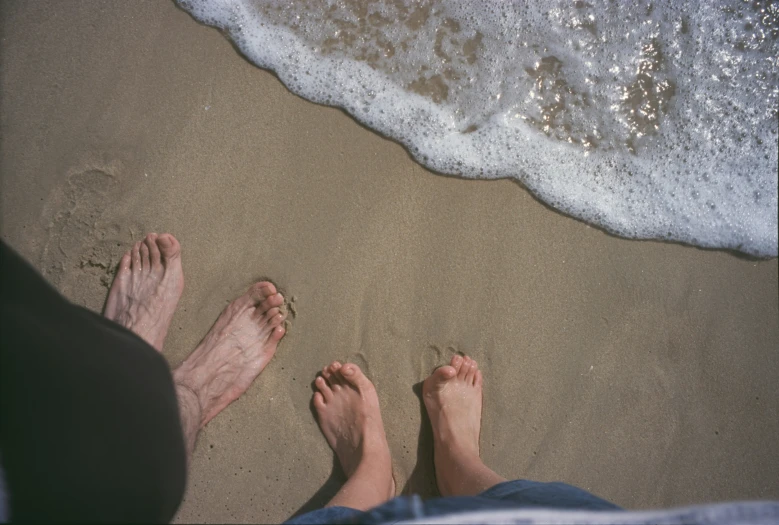 two people feet at the bottom of a beach