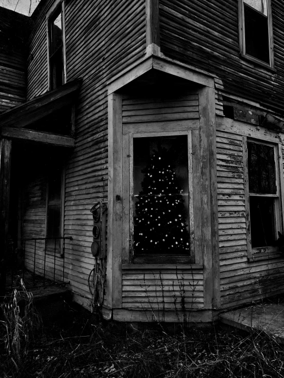 a black and white po of a lit christmas tree in the windows