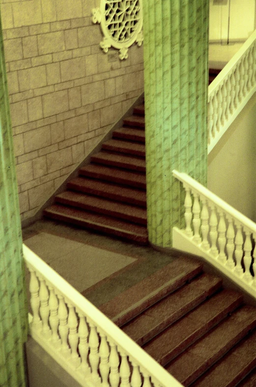 staircase and ornate columns with decorative windows, with green curtains and carpeting