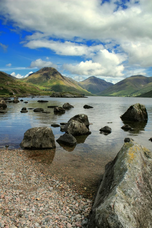 some rocks and water with hills in the background